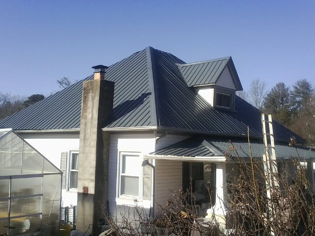 Dark blue standing seam metal roof on a white farmhouse with dormer — Slate & Tile Roof Repair by Roofing Brothers in Duluth