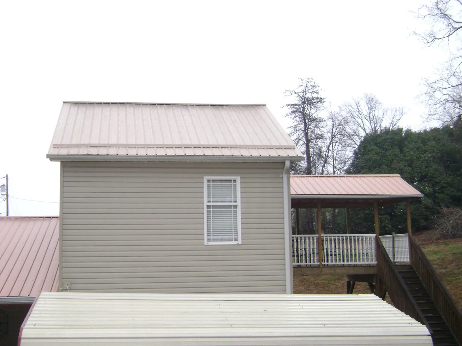 Tan metal roofs on a two story addition and attached porch, from a Roof Replacement job in Duluth